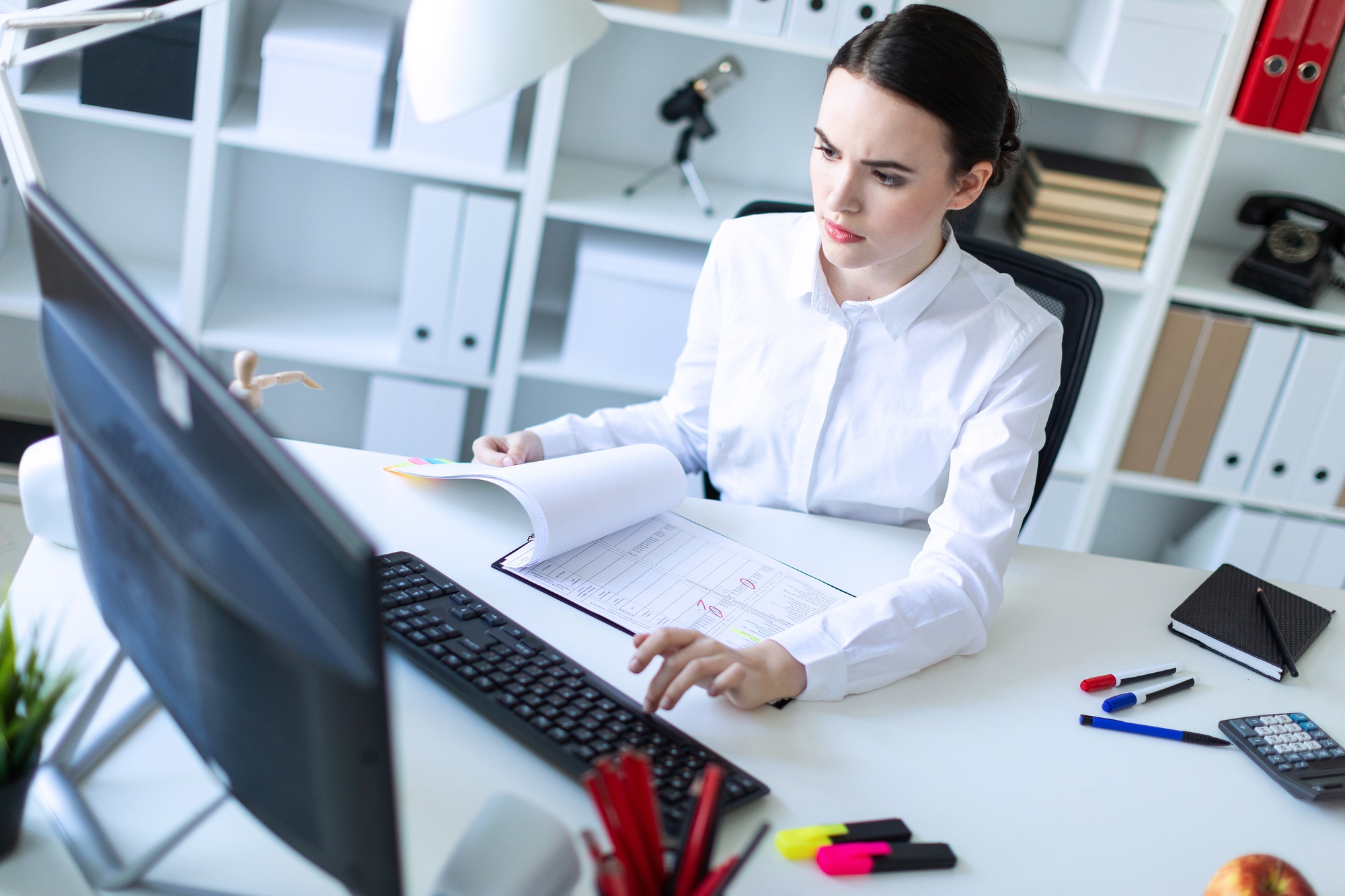 Young girl in the office working with documents at the computer.